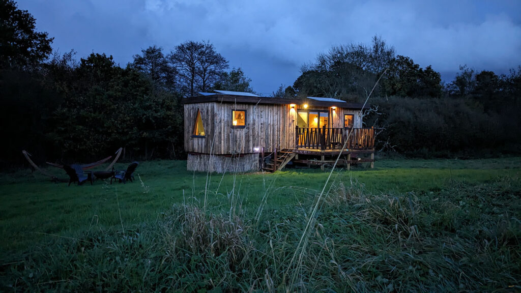 a welcoming glamping log cabin at sussex in the field at night with soft lighting