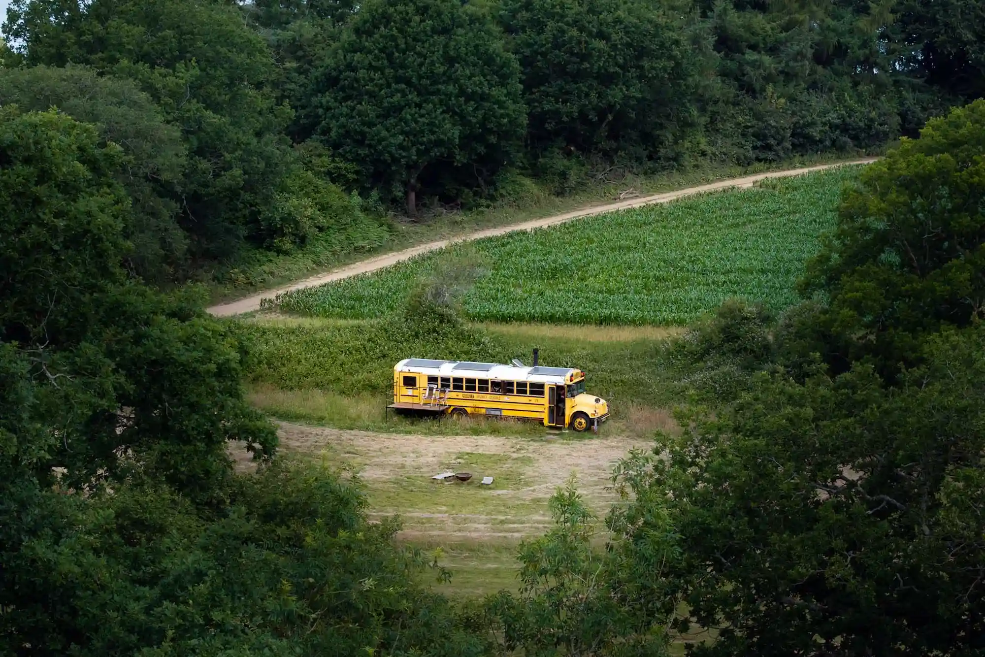 Drone shot of the Skoolie Stays glamping bus in a secluded West Sussex meadow