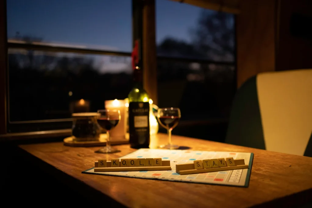 Cosy slow-living evening inside the Skoolie Stays bus with candles, wine and a board game during a digital detox break