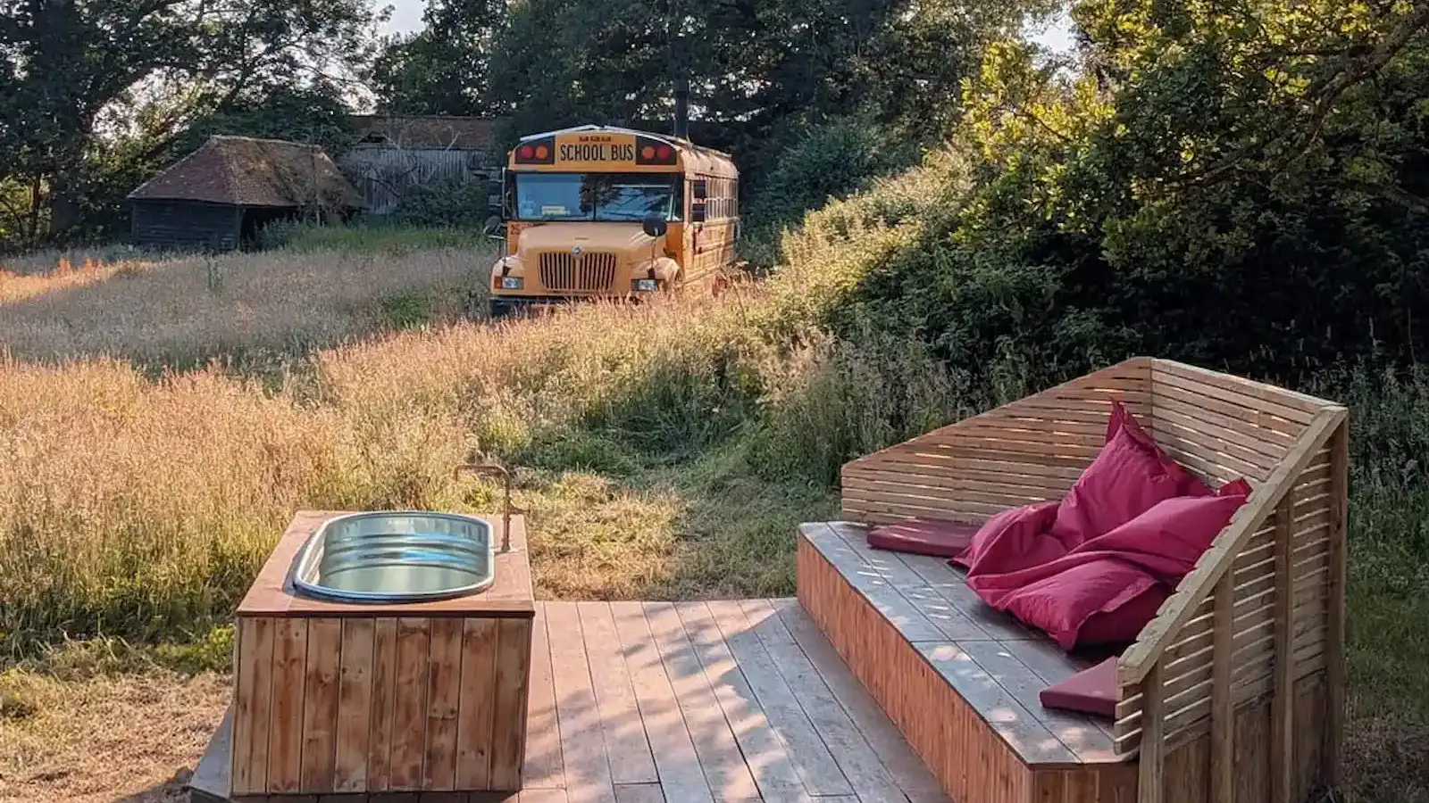 Outdoor wood-fired hot tub beside a converted American school bus in a Sussex meadow