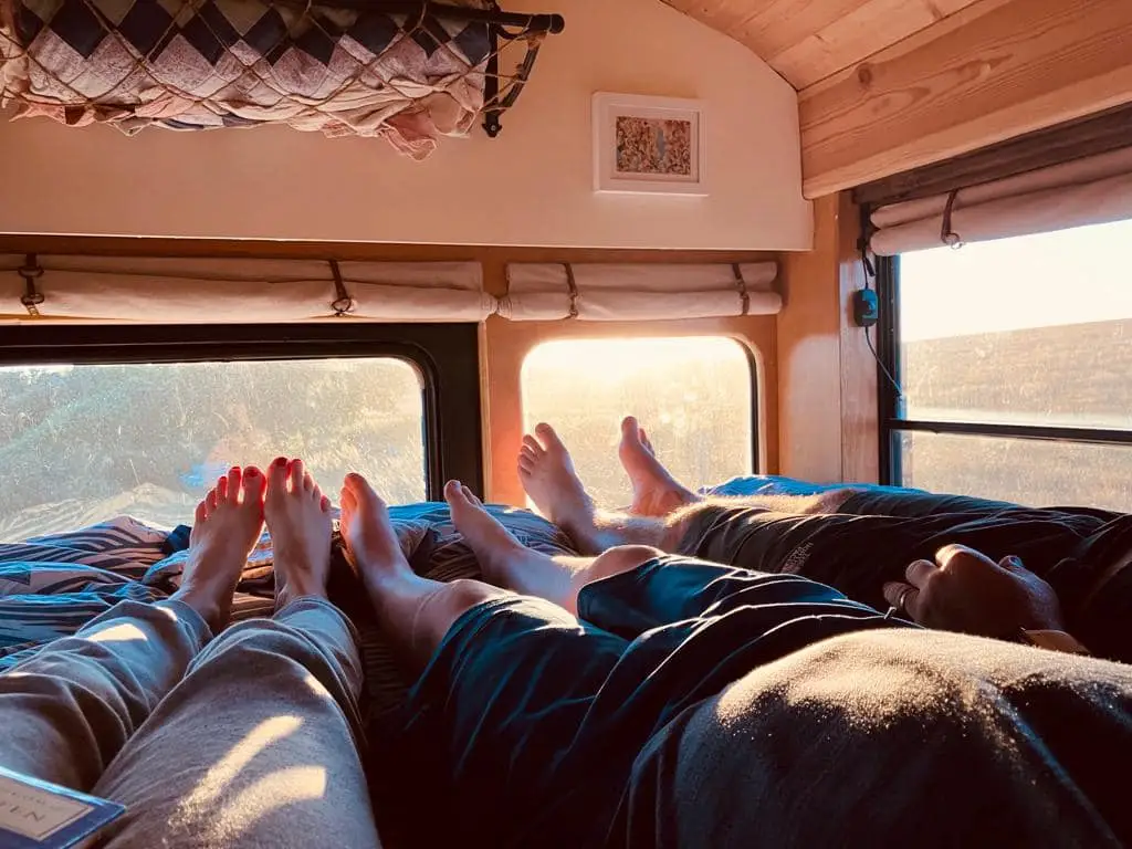 Relaxing in bed inside a converted American school bus, looking out over the Sussex countryside