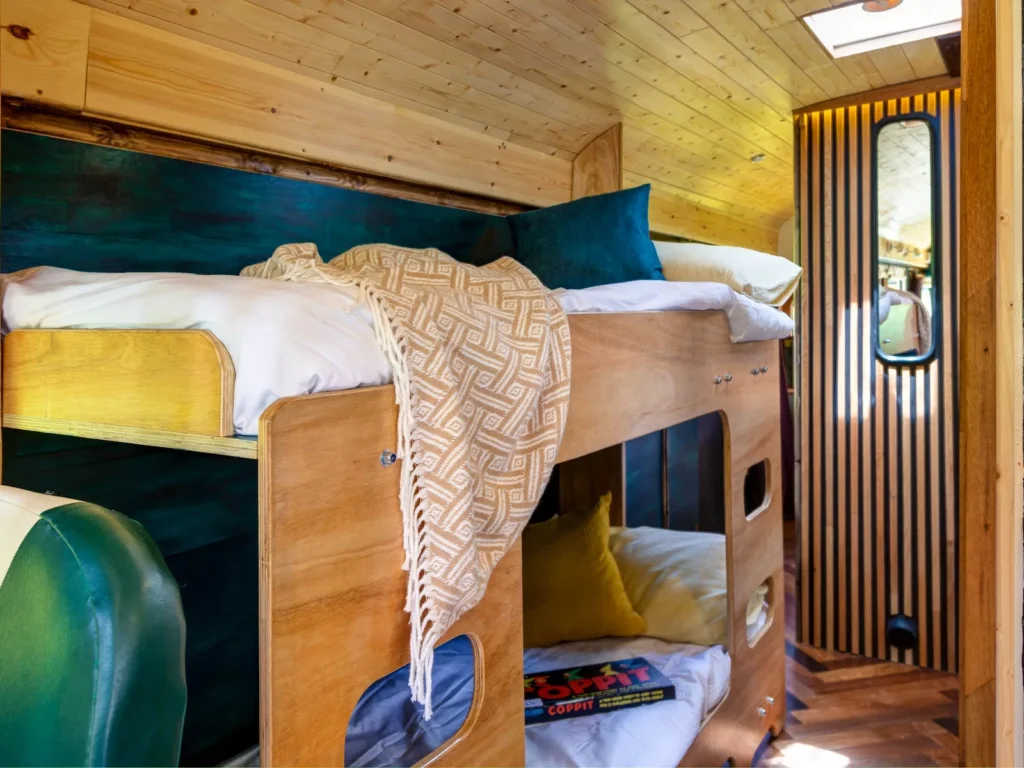 Cosy sleeping area inside the converted American school bus at Skoolie Stays