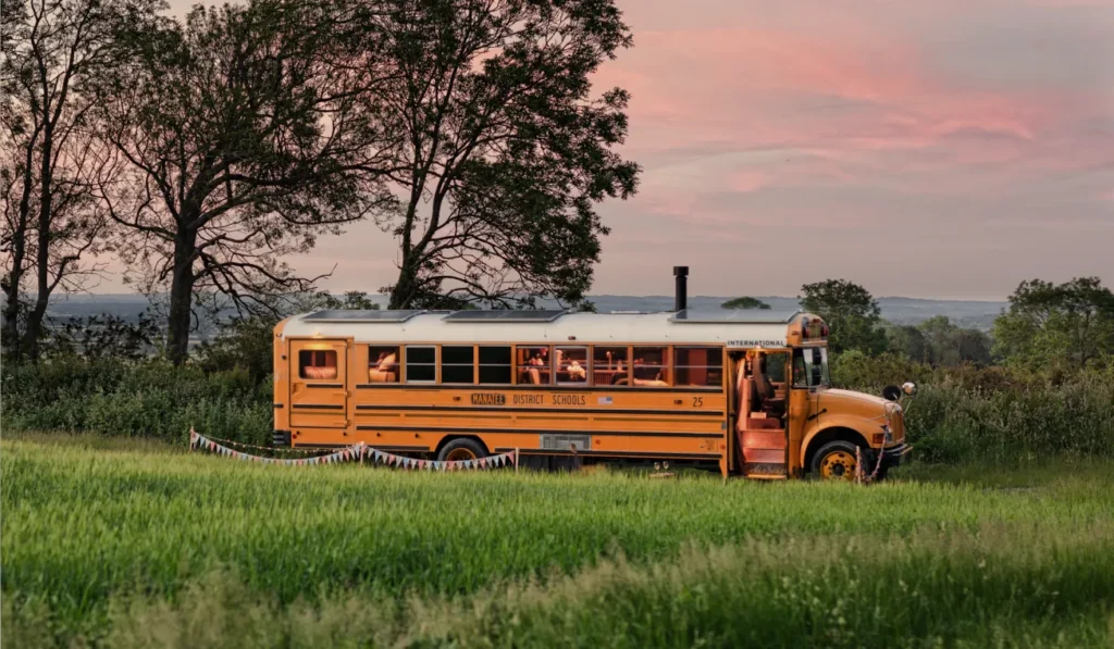 Converted American school bus glamping stay at sunset in the Sussex countryside