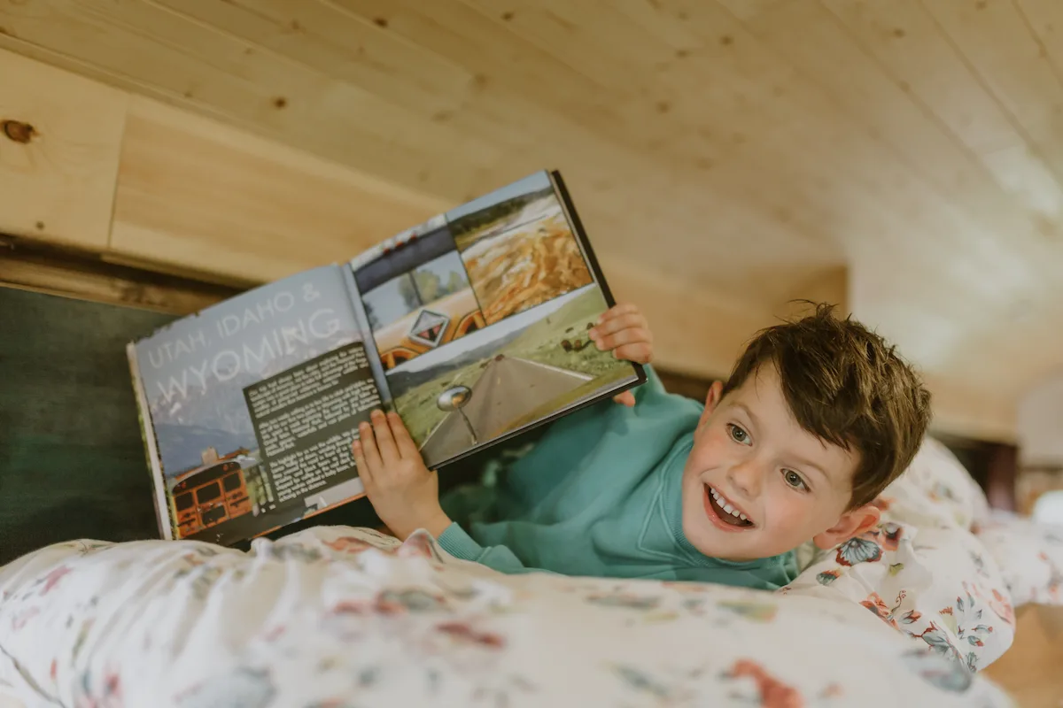 Child reading in bed during a family digital detox break at Skoolie Stays